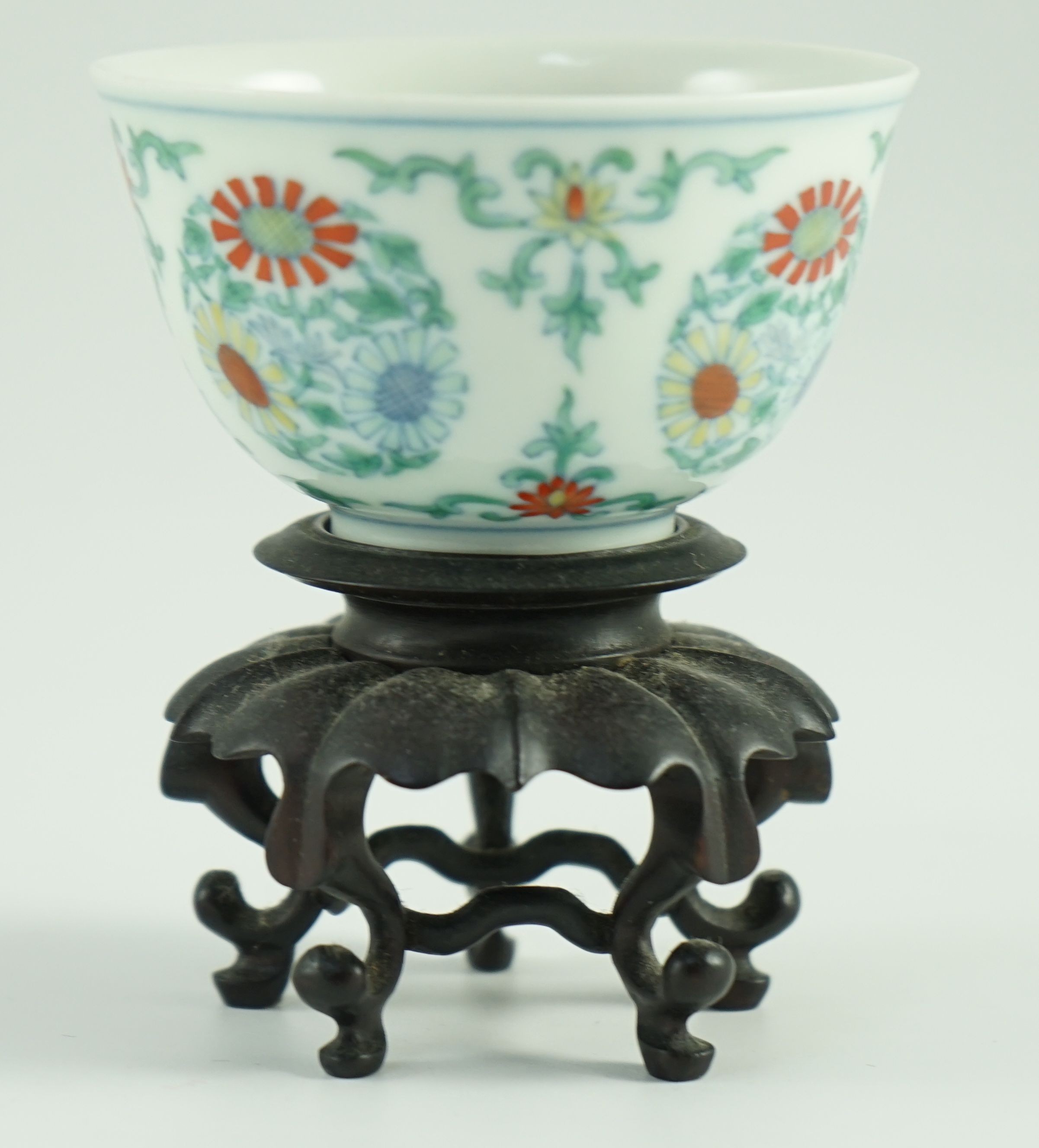 A Chinese doucai ‘chrysanthemum medallion’ cup, Yongzheng mark, probably late 19th/early 20th century, 7.2cm diameter, wood stand